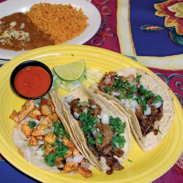 Three tacos, two with steak and one with chicken, on a yellow plate with rice and beans.