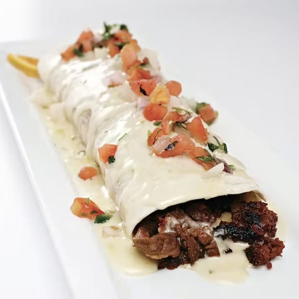 A large burrito from Palacio Maya, smothered in white sauce, topped with pico de gallo.