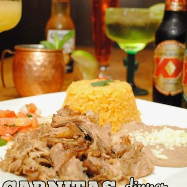 Palacio Maya's carnitas dinner with rice, beans, pico de gallo, and drinks in the background.
